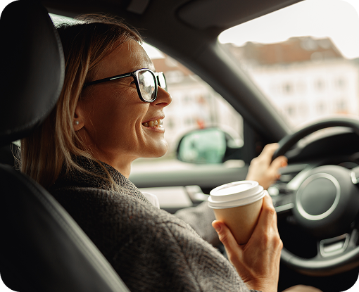 A driver holding a coffee cup behind the wheel