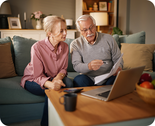 An older couple reviewing paperwork at a laptop