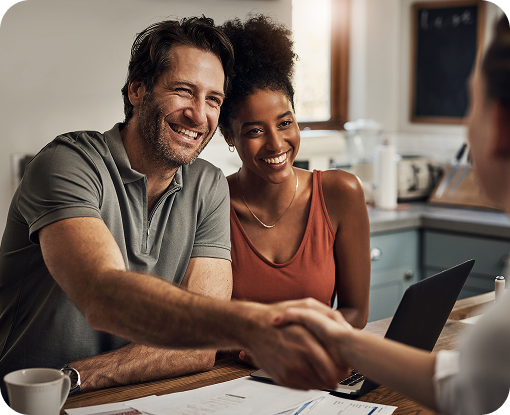 Two people shaking hands across a table at home