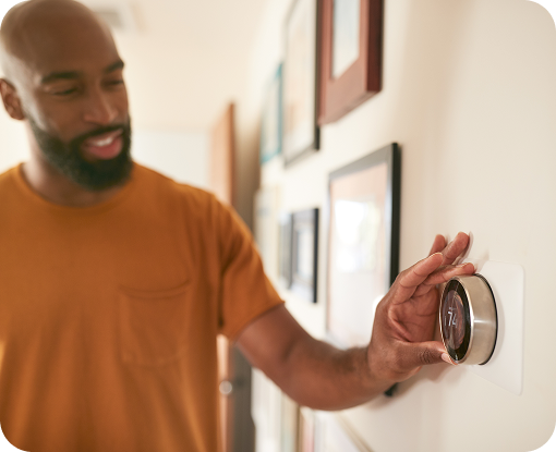 A person adjusting a wall thermostat
