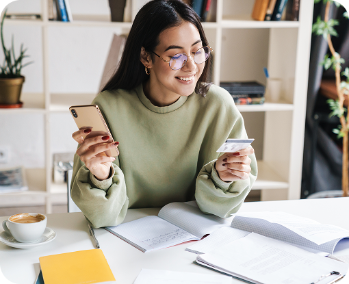A person holding a phone at a desk with paperwork and a laptop