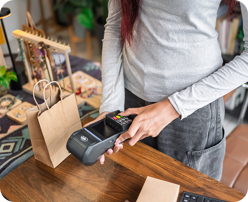 A person tapping a card on a payment terminal at a market stall