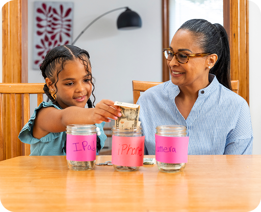 A child and grandparent with three savings jars on a table