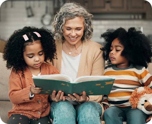 A grandparent reading a book with two children on a sofa