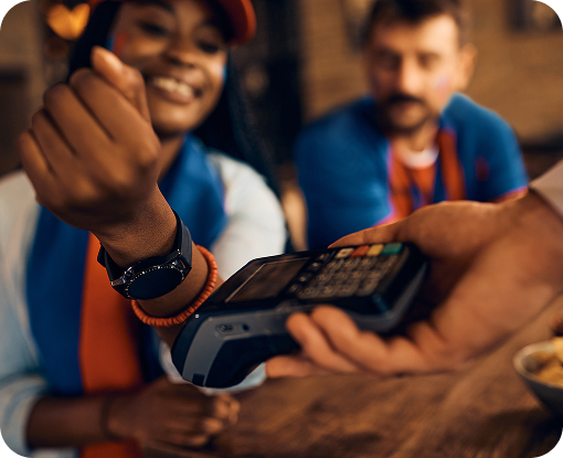 A customer tapping a phone on a card reader held by a shop worker