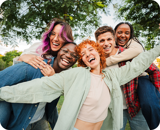 A group of friends hugging and laughing outdoors