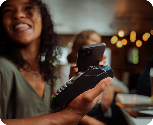 A person smiling while looking at their phone in a bar