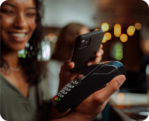 A person smiling while using their phone in a bar