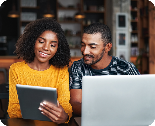 Two people looking at a tablet and laptop together