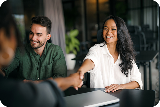 Two people shaking hands across a table