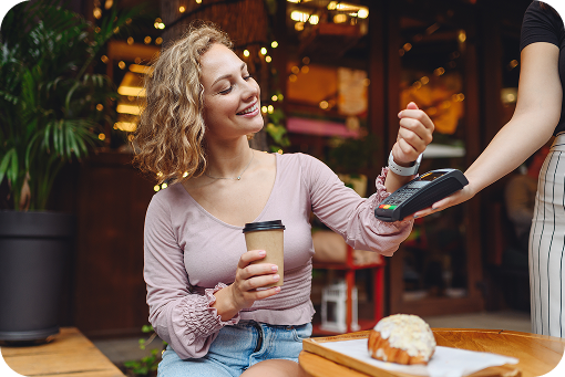 A customer paying by phone at a coffee shop counter