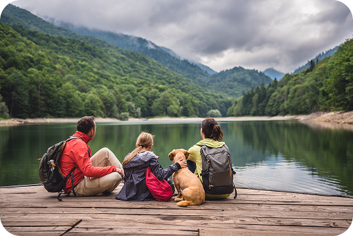 A family sitting on a jetty looking out over a mountain lake