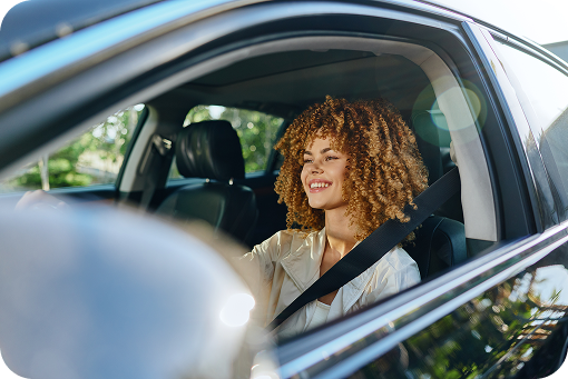 A person smiling in the driver's seat of a car