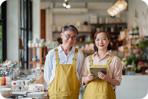 Two shop workers in aprons looking at a phone together