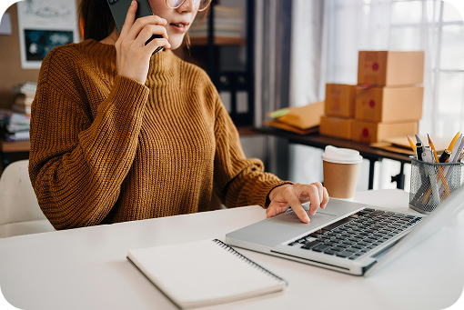 A person on the phone at a desk with parcels behind them