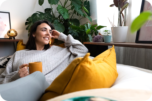 A person relaxing on a sofa with a mug