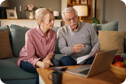An older couple reviewing paperwork at a laptop