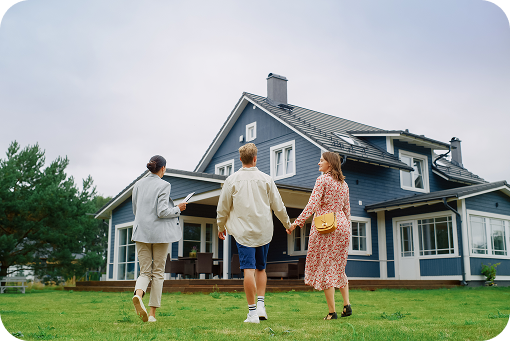 A family walking across a lawn towards a large house