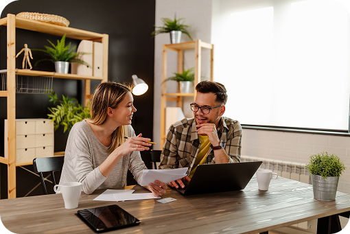 Two people talking over a laptop at a kitchen table