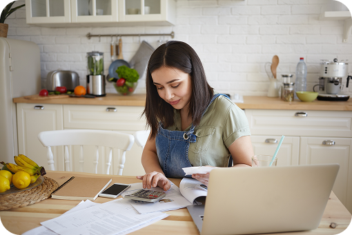A person working at a laptop at a kitchen table
