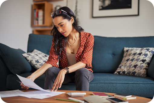 A student working at a laptop with paperwork on a sofa