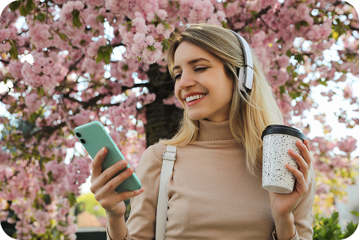 A person using a phone outdoors under blossom trees