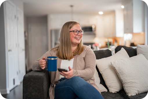 A person holding a mug while sitting on a sofa