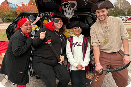 Three people in Halloween costumes posing together at a community event