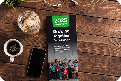 A printed 2025 community impact report on a desk beside a coffee cup and phone