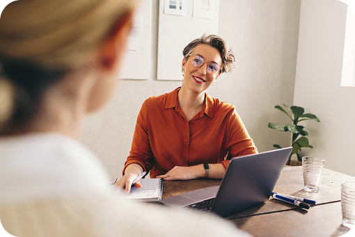 A Waypoint employee smiling across a desk at a visitor during a meeting